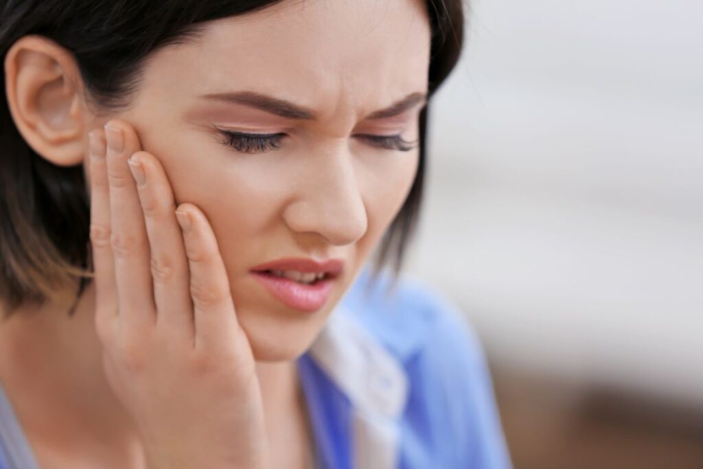 A woman clutching her jaw in pain.