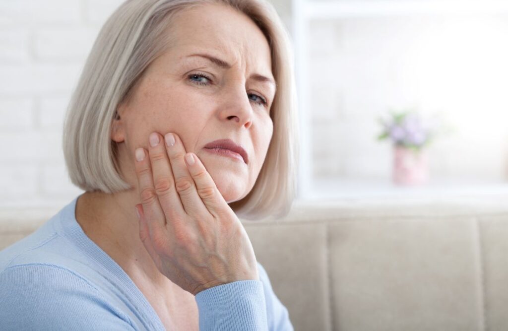 A woman clutching her jaw in pain.